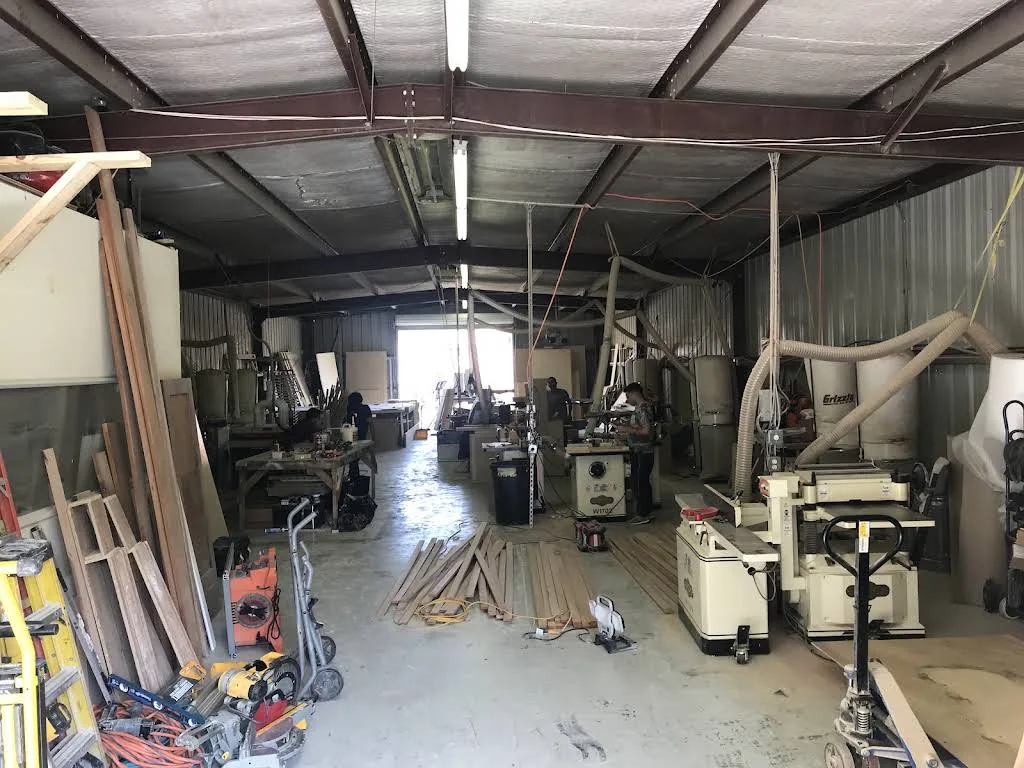 RM cabinet workshop with woodworking machines, lumber and cabinet frames.
