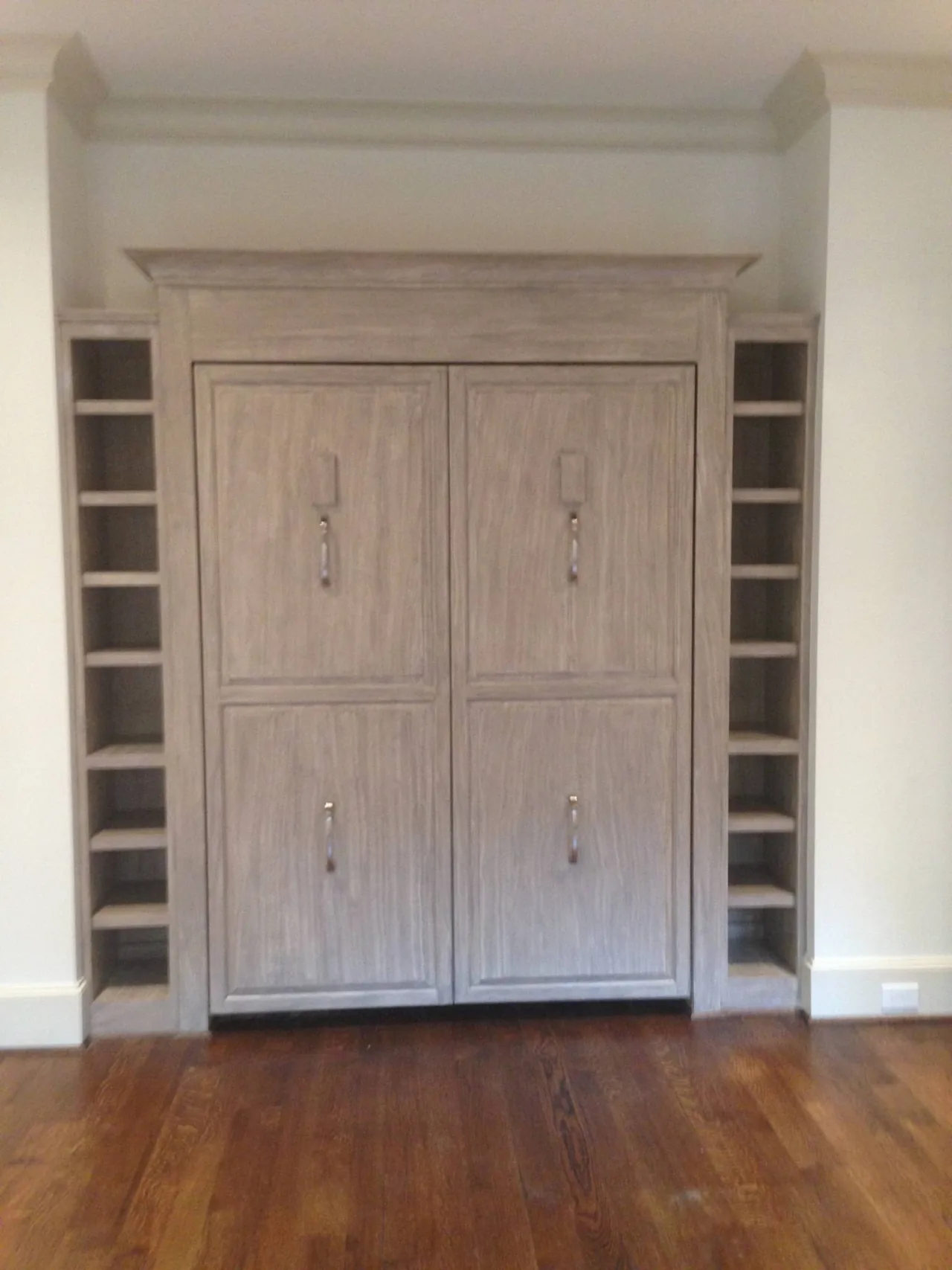 RM built-in bed folded closed, with gray paneled fronts and shelves on both sides.