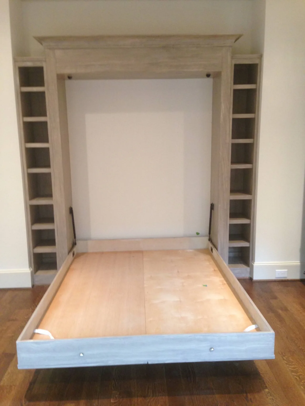 The same built-in bed opened, showing its bare platform and side shelving.